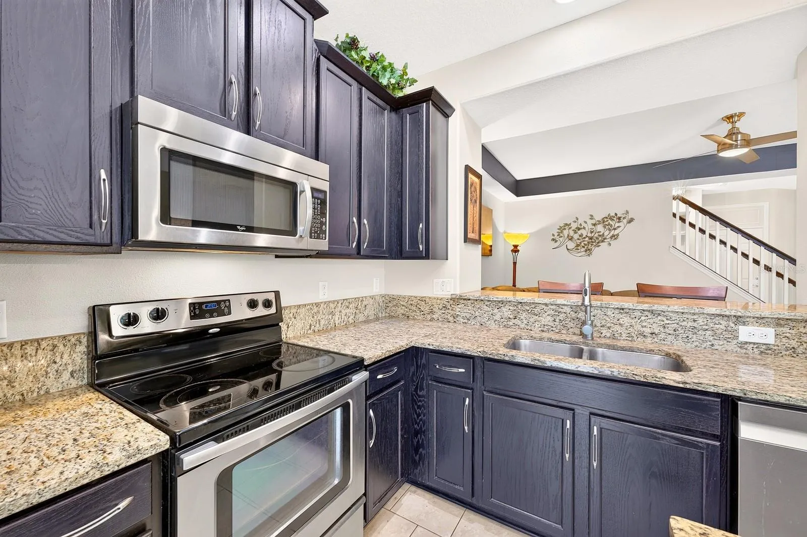 The nearby Kitchen is both stylish and functional, offering an abundance of 42-inch cabinetry, STONE COUNTERTOPS, a center island, STAINLESS STEEL APPLIANCES, including a NEWER DISHWASHER (2022), and a spacious breakfast bar.