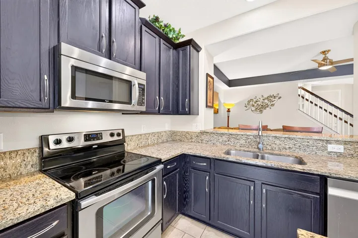 The nearby Kitchen is both stylish and functional, offering an abundance of 42-inch cabinetry, STONE COUNTERTOPS, a center island, STAINLESS STEEL APPLIANCES, including a NEWER DISHWASHER (2022), and a spacious breakfast bar.