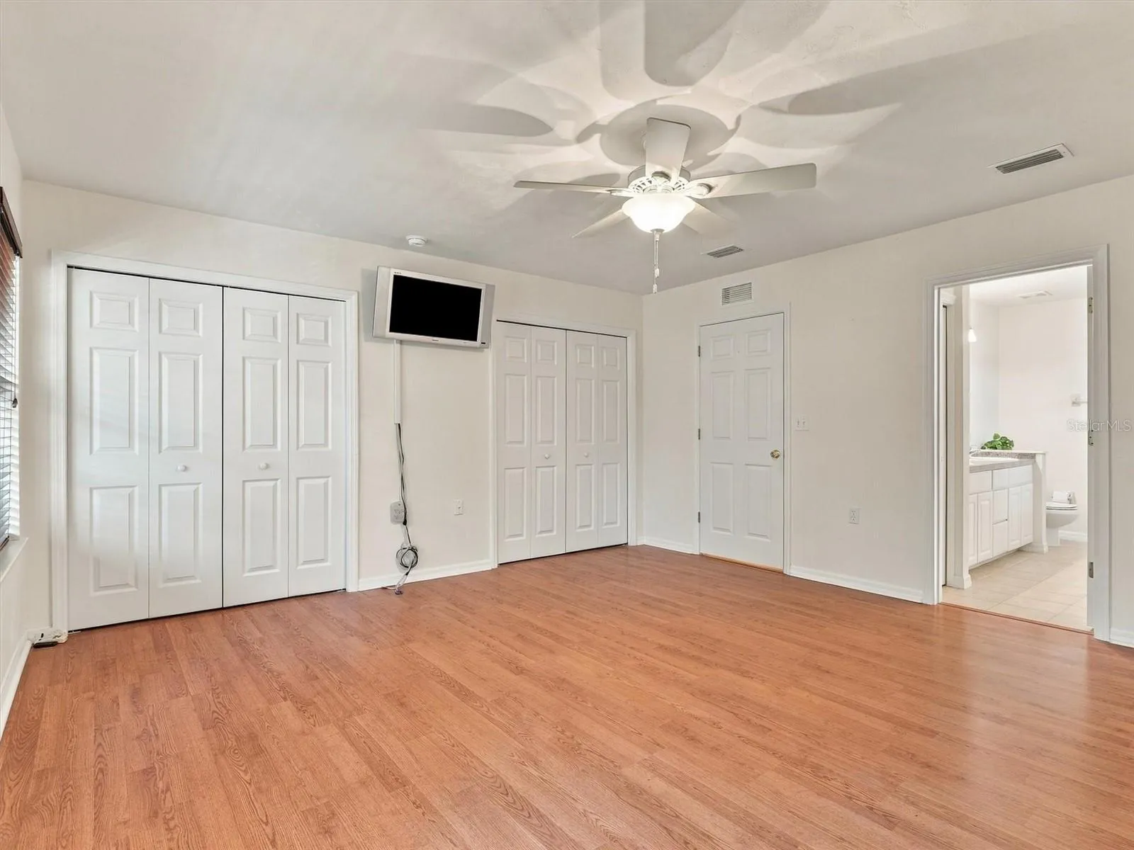 Primary Bedroom, Dual Closets, En-Suite Bathroom, Mounted TV, door to hallway.