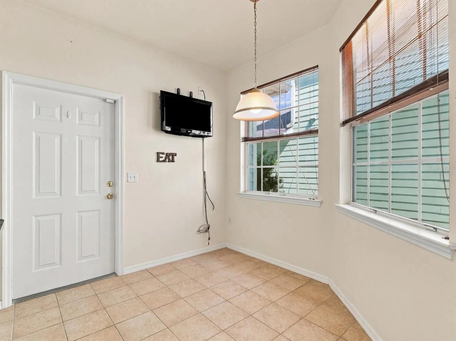 Virtually Staged - Dinette & Kitchen with light from windows, mounted tv, and door to garage.