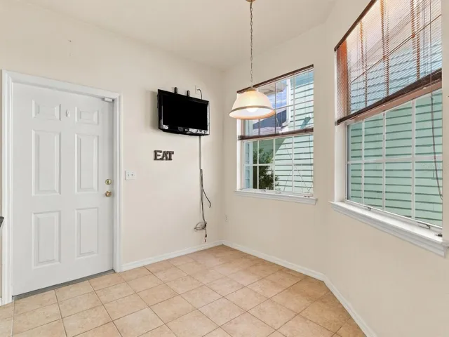 Virtually Staged - Dinette & Kitchen with light from windows, mounted tv, and door to garage.