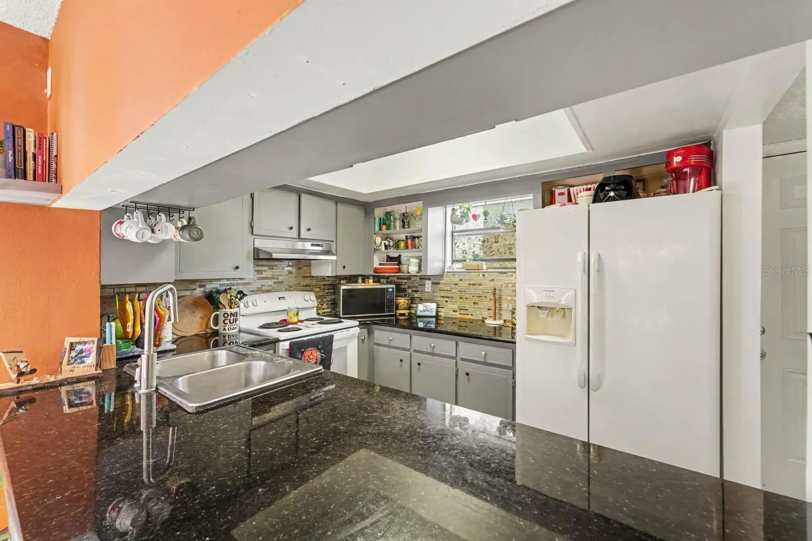Complete kitchen view with dual sinks, cream refrigerator &amp; brick backsplash detail
