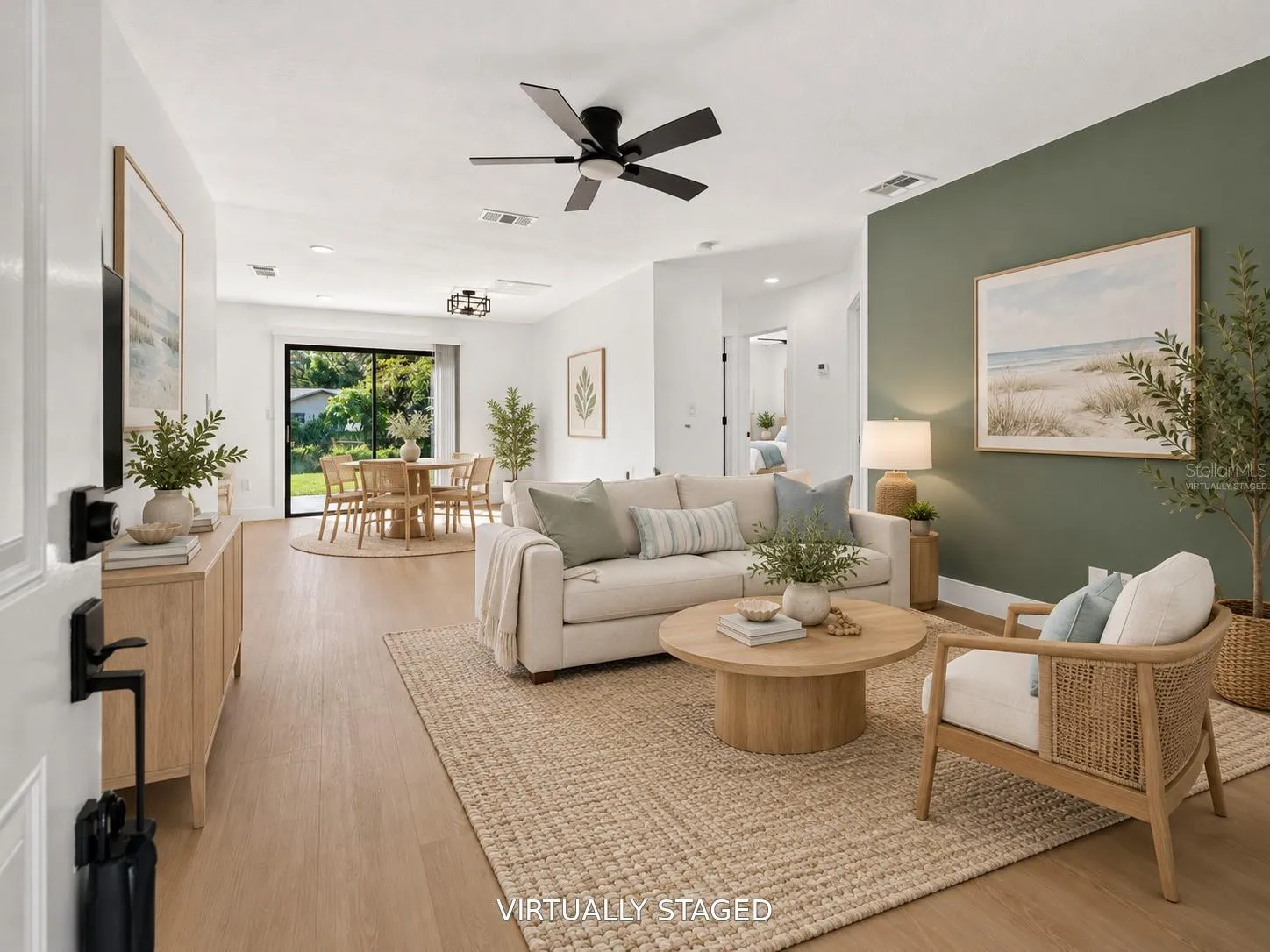 VIRTUALLY STAGED. Spacious living area featuring a modern sage green accent wall.