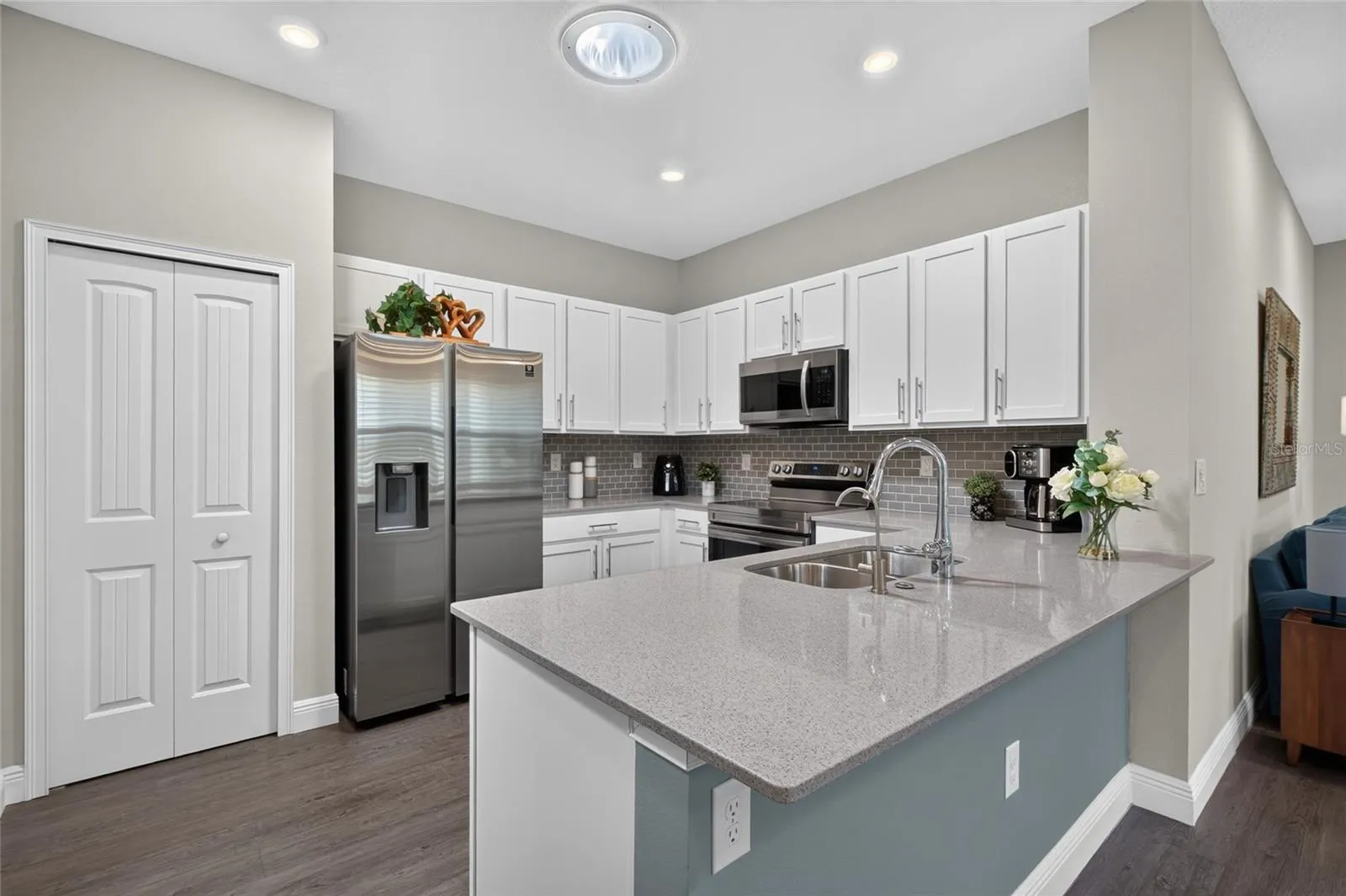 Kitchen with white shaker cabinets, tile backsplash, stainless steel appliances.