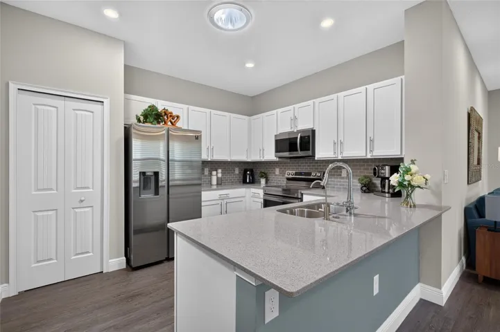 Kitchen with white shaker cabinets, tile backsplash, stainless steel appliances.