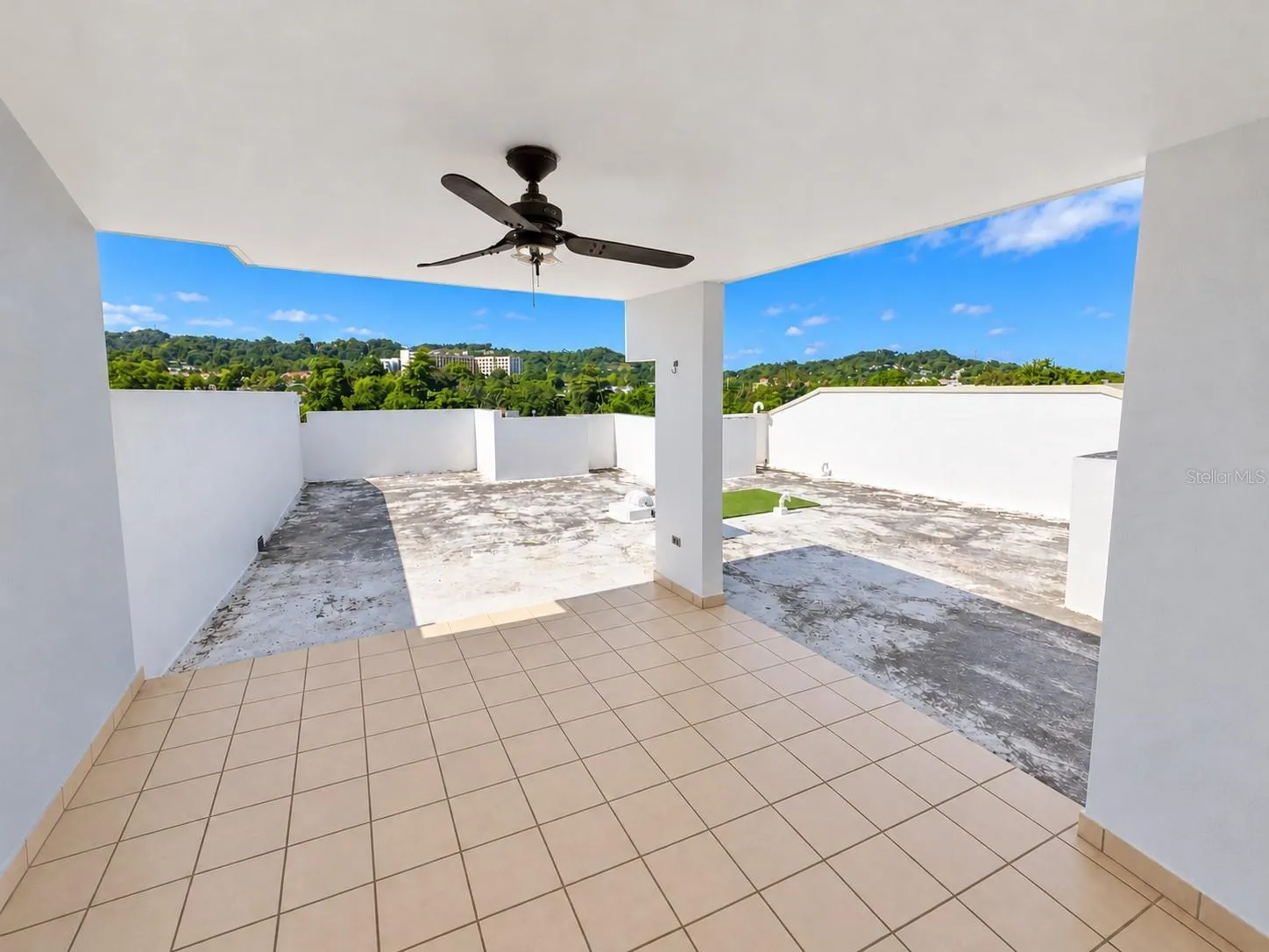 Upper-level terrace with a covered seating area and views of the surrounding hills.