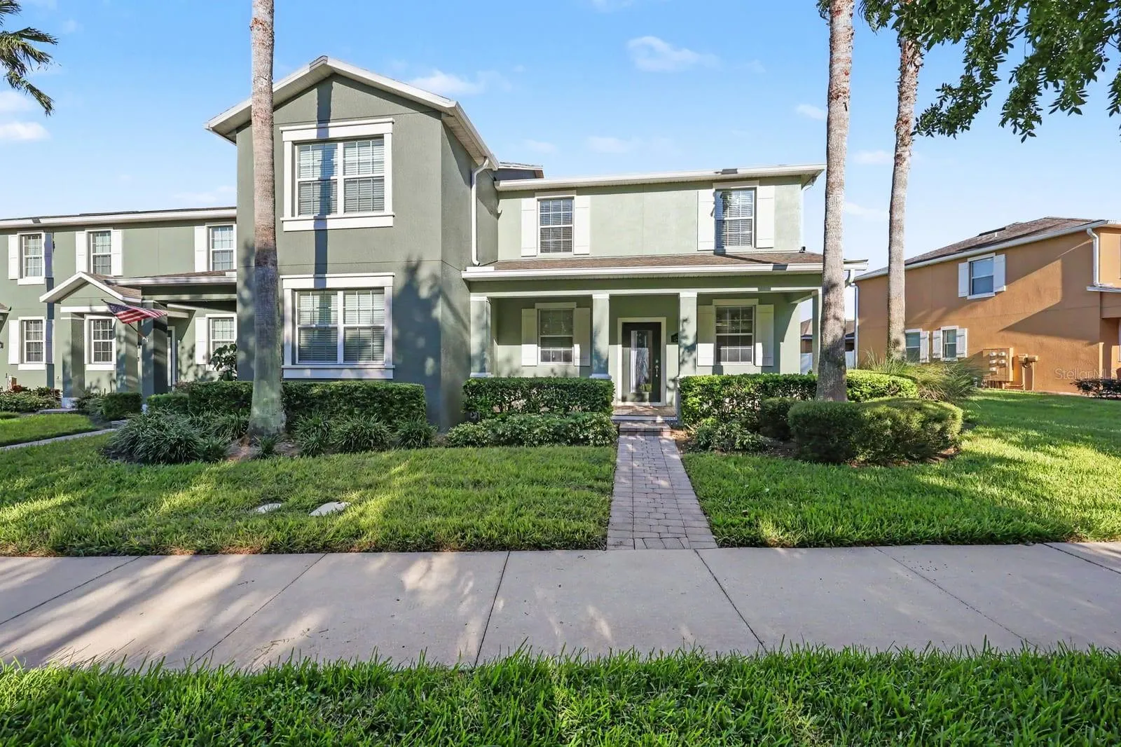 Charming two-story home with green exterior and manicured landscaping