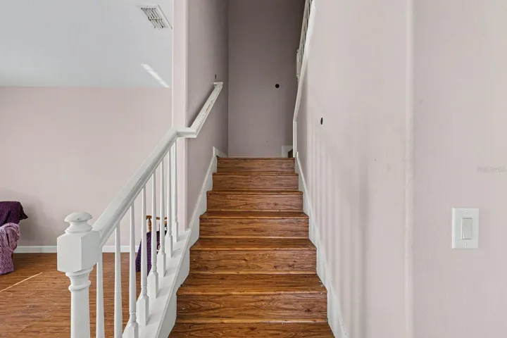 Staircase With White Rails &amp; Wood Steps Connects Upper &amp; Lower Levels