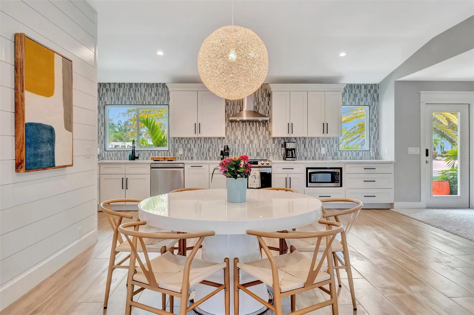 Extensively updated with 2023 roof, 2022 AC, newer rear windows, flood barriers, wood-look tile, neutral finishes, and open living/dining area.