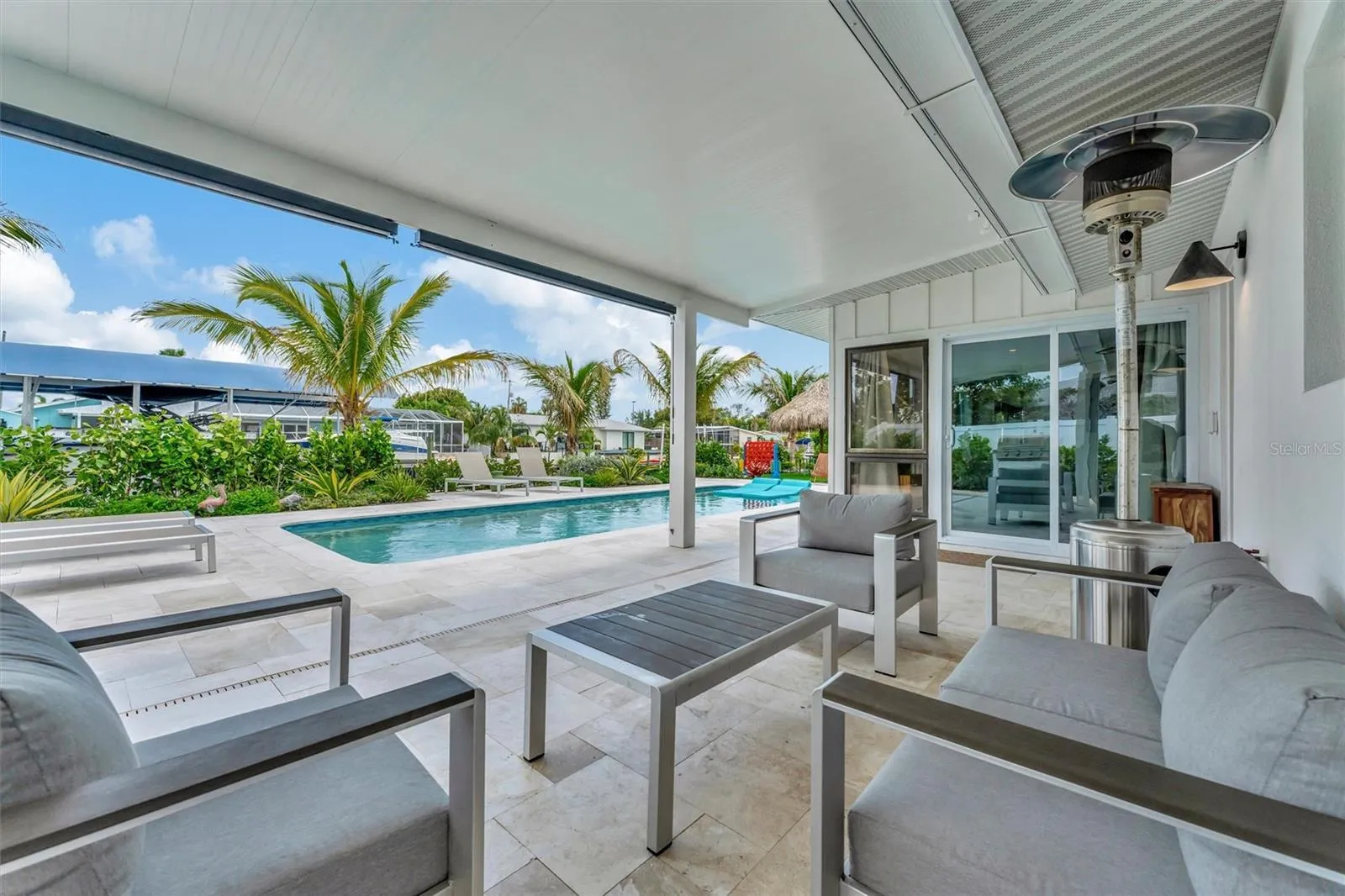Heated saltwater pool, covered lanai, outdoor terraces, built-in propane grill, and tiki hut with turf games area.