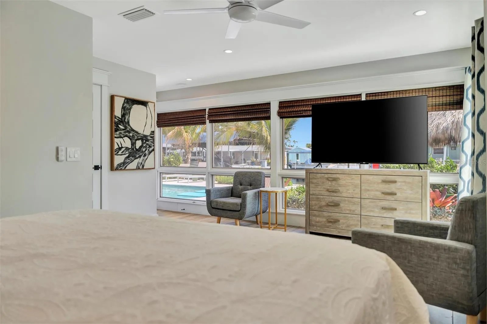 Primary suite with sliding glass doors, gorgeous views of the pool, turf area, and canal, plus an ensuite bathroom.