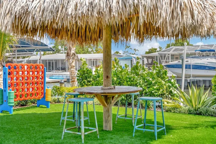 Covered lanai, multiple terraces, built-in propane grill, and tiki hut with turf games area.