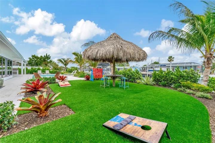 Covered lanai, multiple terraces, built-in propane grill, and tiki hut with turf games area.