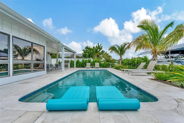Heated saltwater pool, covered lanai, outdoor terraces, built-in propane grill, and tiki hut with turf games area.