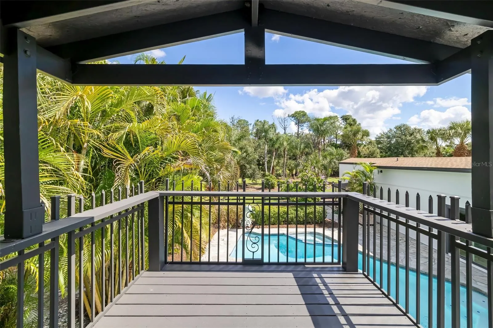 Second-floor primary bathroom opens to a private covered balcony with relaxing views over the pool and surrounding tropical landscape.