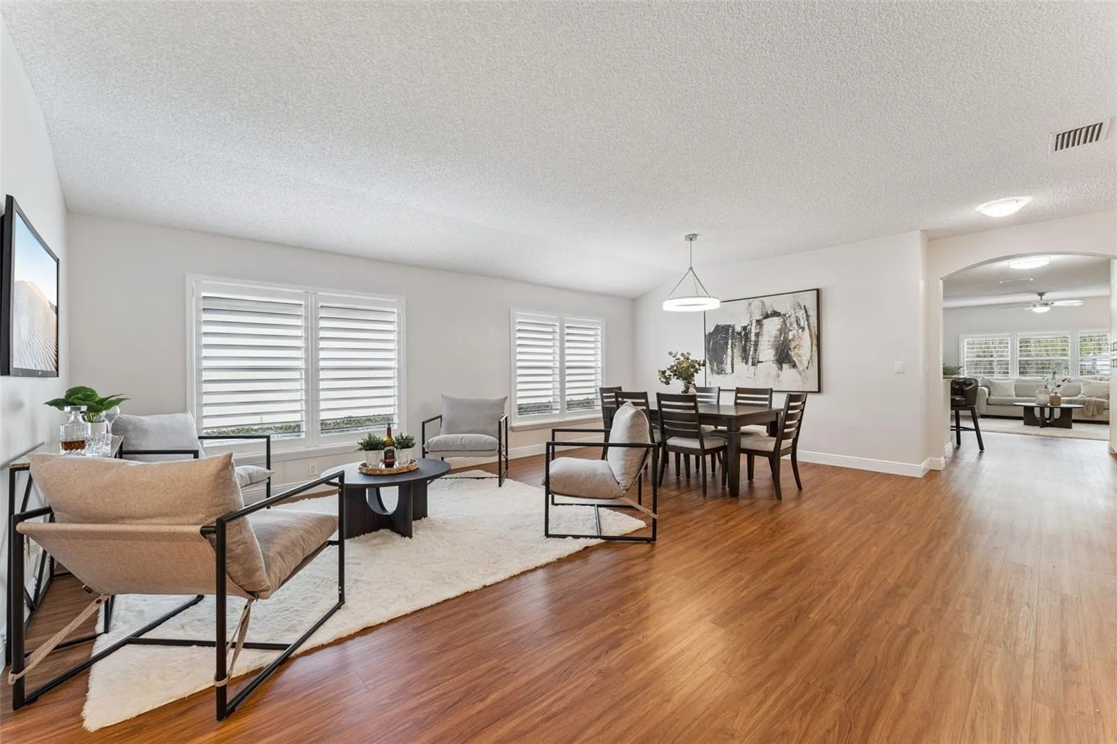 View of the Living &amp; Dining Room areas w/ Plantation style shutters &amp; a laminate floor