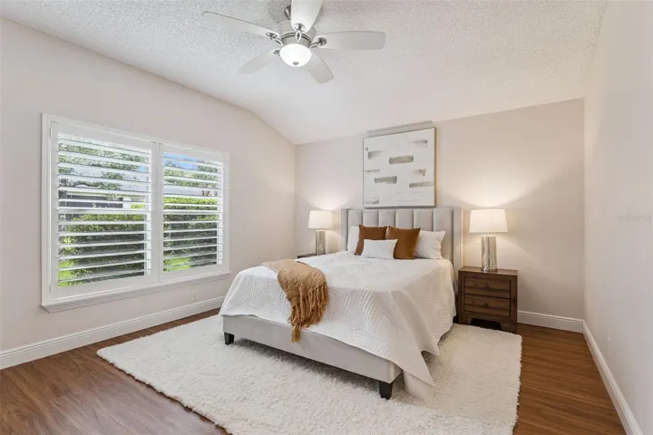 15'6" x 12'6" Primary Bedroom w/ a laminate floor, ceiling fan &amp; Plantation style shutters