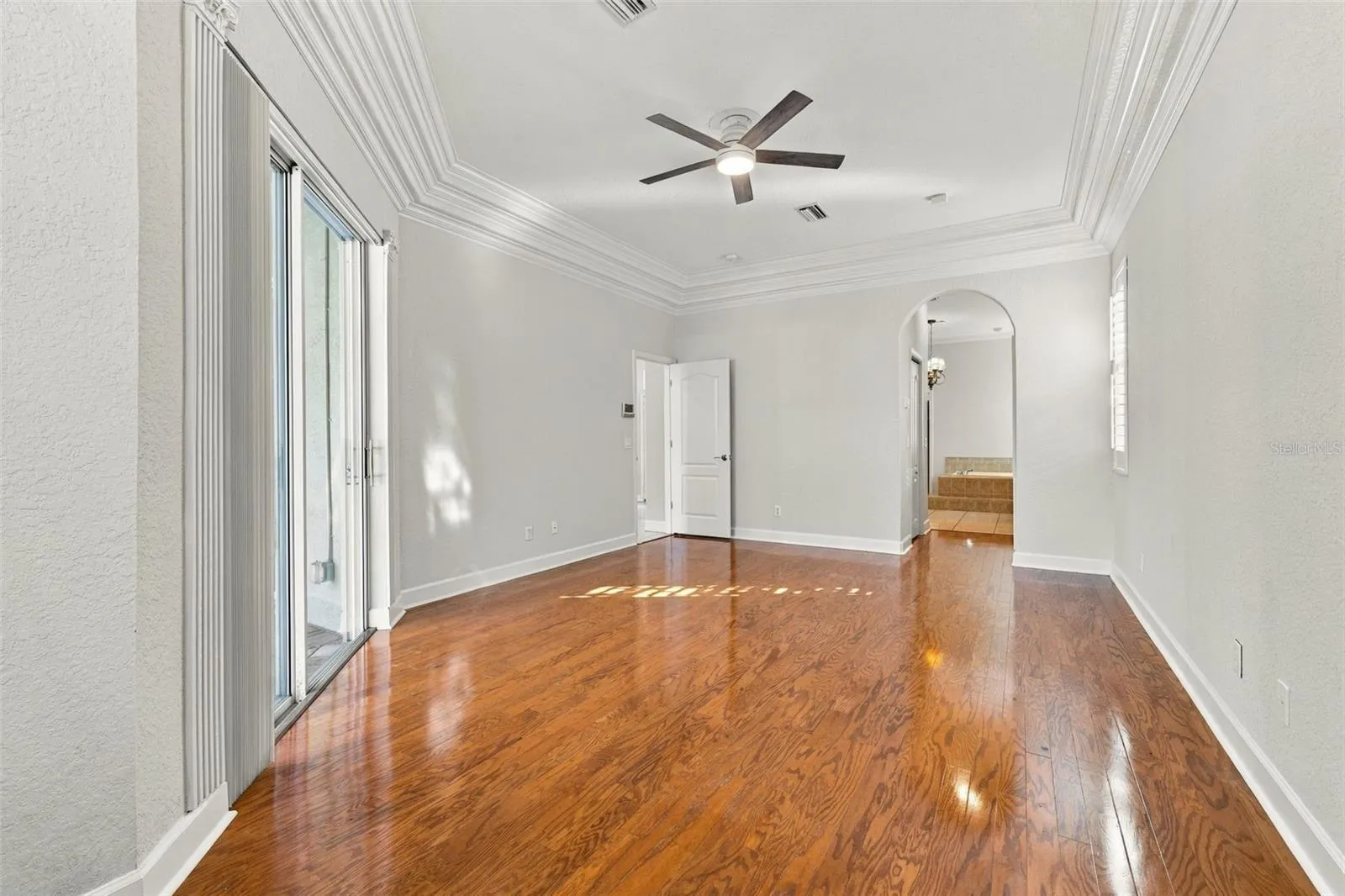 Primary Bedroom with Double Step Tray Ceiling adorned with Crown Molding, Sliding Glass Door to Pool/Spa area &amp; Real Wood Floors!