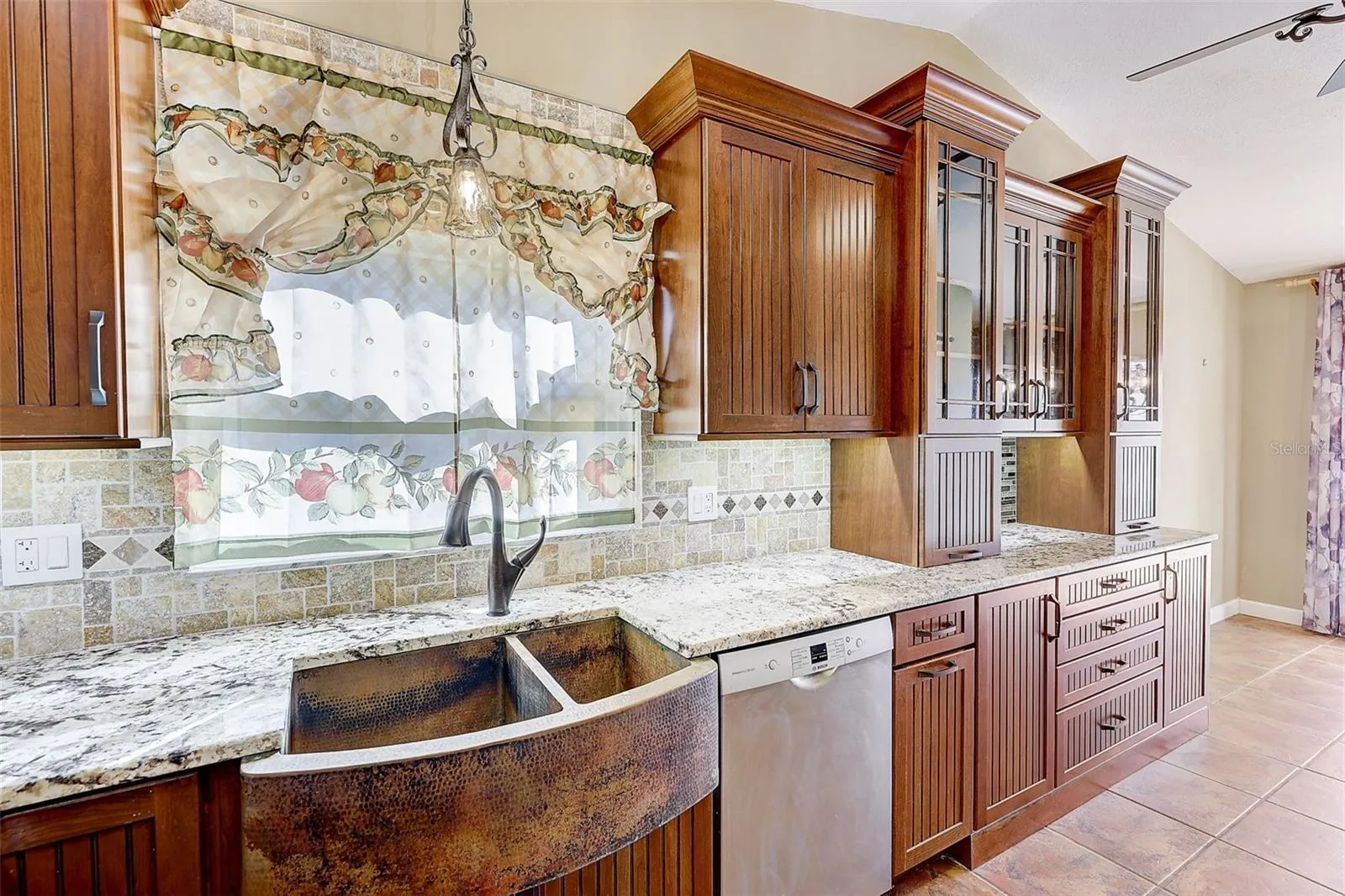 The custom-renovated kitchen, completed in 2021, is a standout feature, offering custom cabinetry with soft-close doors and drawers, polished granite countertops with natural edges, a custom tile backsplash, a copper undermount sink, and a touch-operated faucet with an integrated pot-filler feature. Additional details include a solid-wood barn door pantry, a built-in cabinet with antique glass doors and interior lighting, under-cabinet lighting, and quality appliances, including a French-door refrigerator, extra-quiet Bosch dishwasher, microwave installed in the lower cabinetry, and LG double oven, complemented by a full-size copper overhead range exhaust hood.