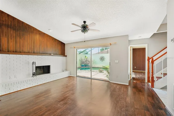 spacious living room with a wood-burning fireplace and laminate floors.