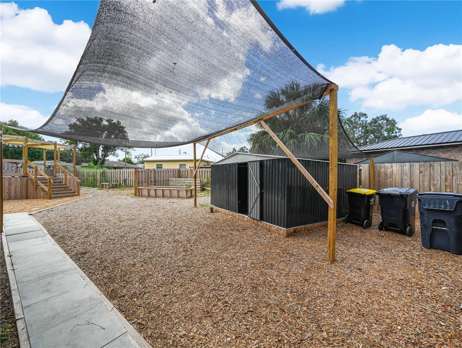 Fully fenced back yard with pool, deck, shed and raised garden beds