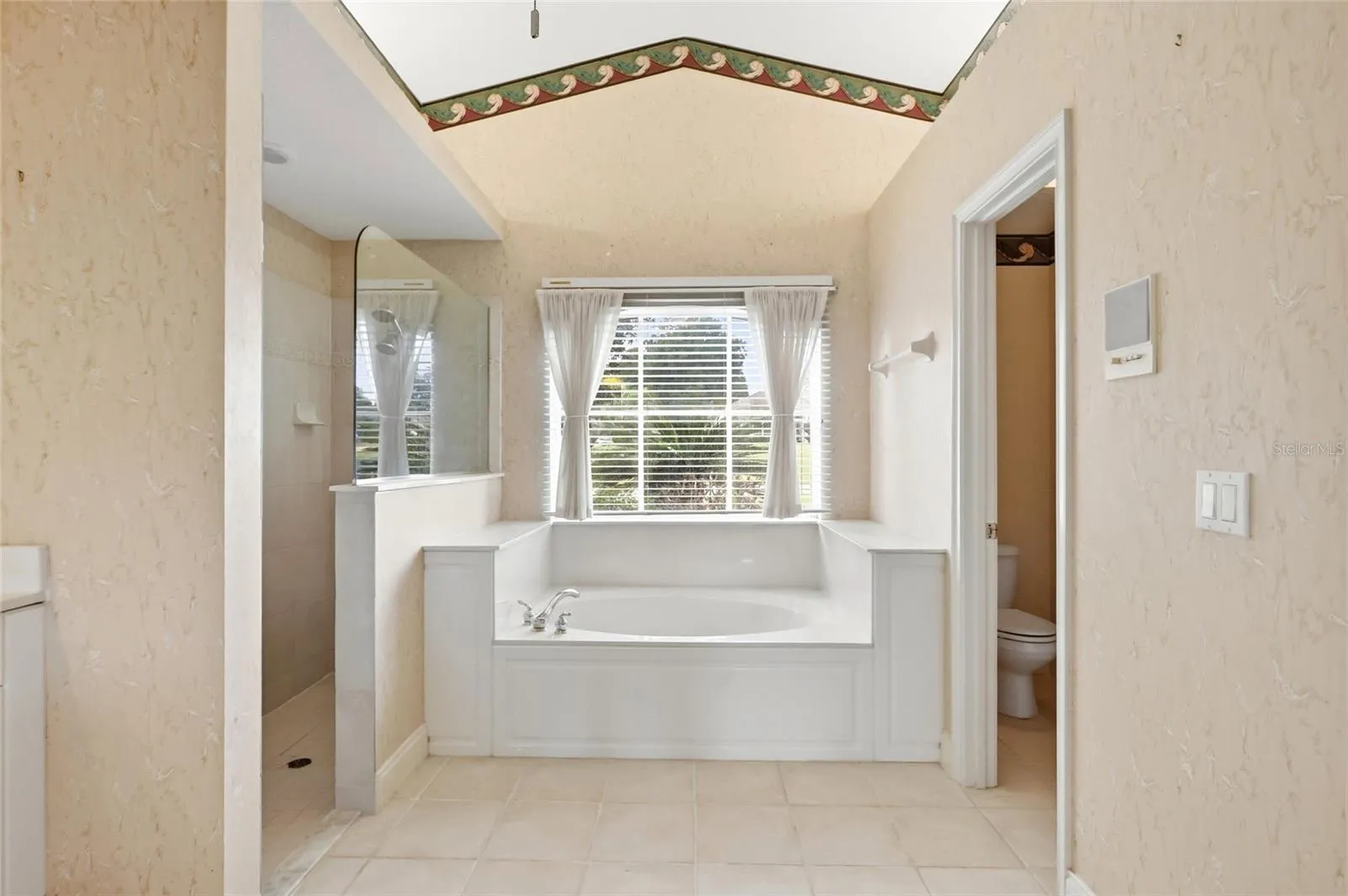 Primary bathroom with a soaking tub beneath a window and a separate shower.