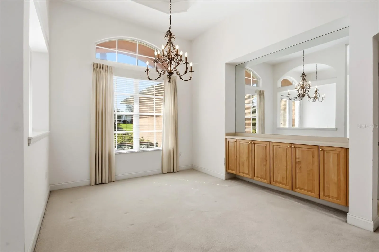 Formal dining room with an arched window, chandelier, and built-in server and storage.