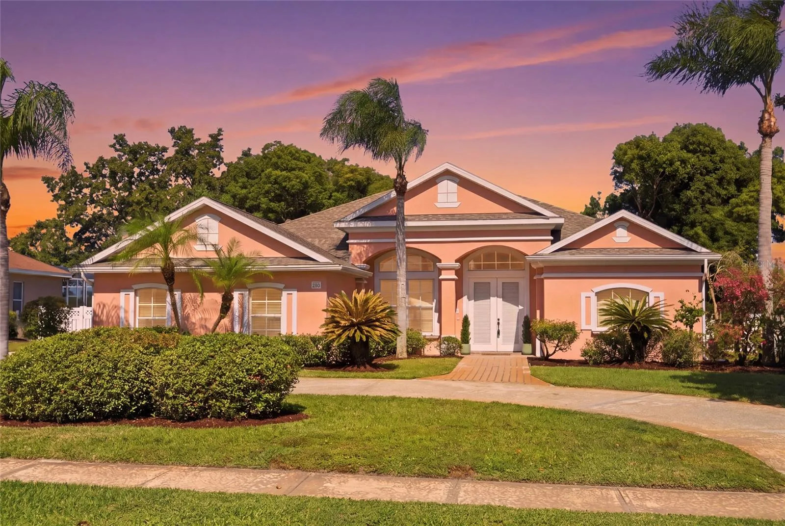 Twilight exterior view of this Glen Abbey home in DeBary, highlighting the palms, maturelandscaping, and covered front entrance.