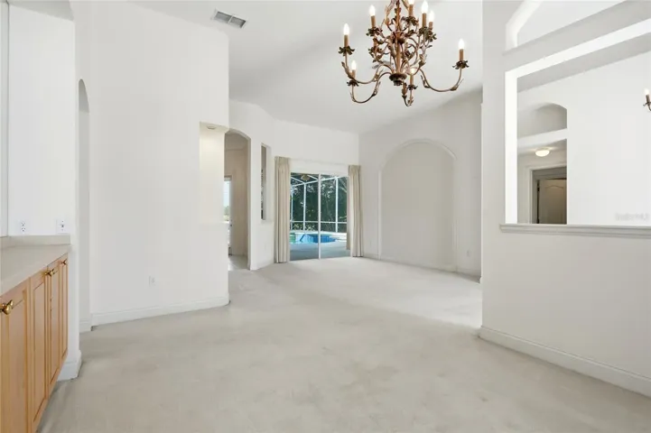 Separate formal living and dining rooms feature high ceilings, with sliding glass doorsconnecting the living room to the pool area.