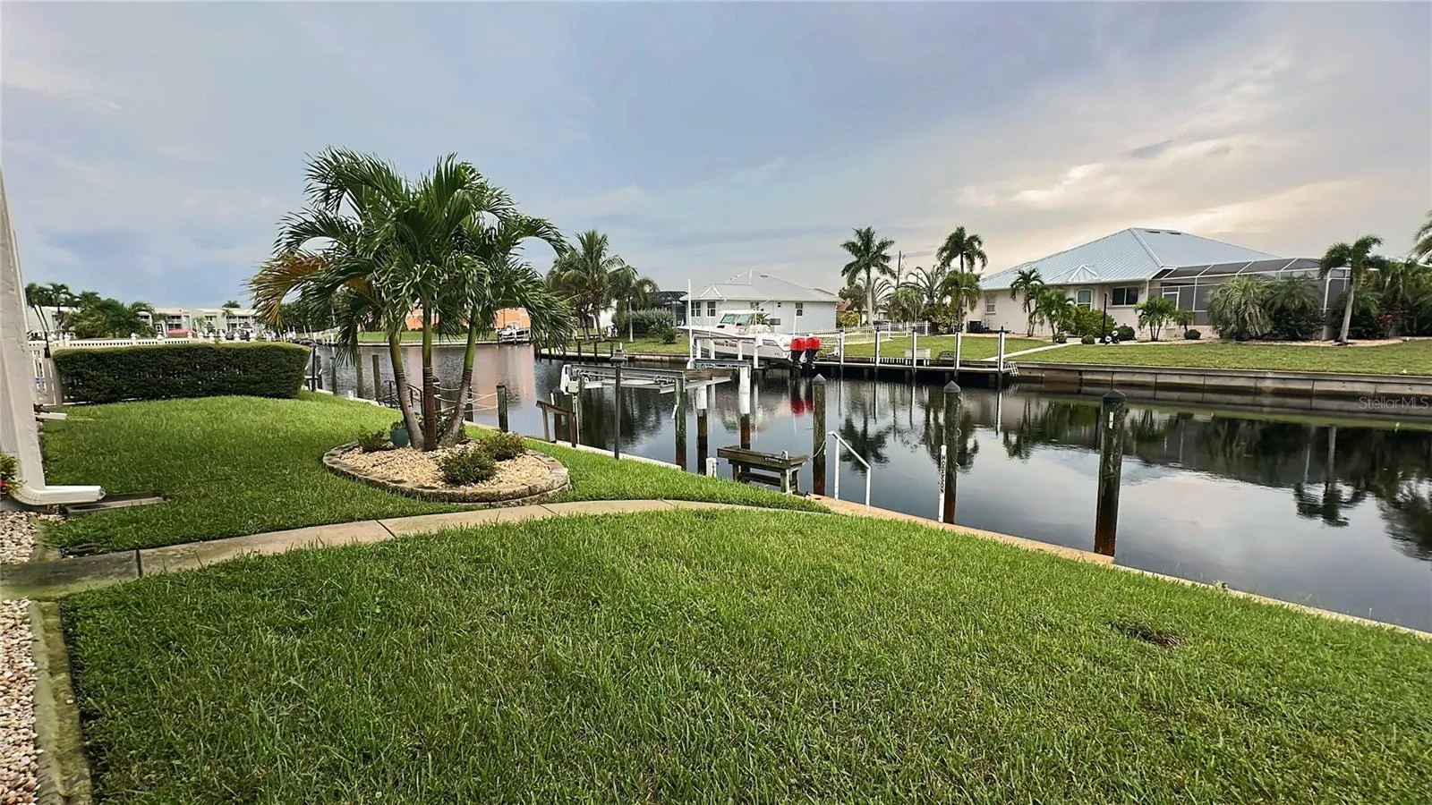 Waterfront lawn with palm landscaping along the canal behind the condo, a short walk to the dock.