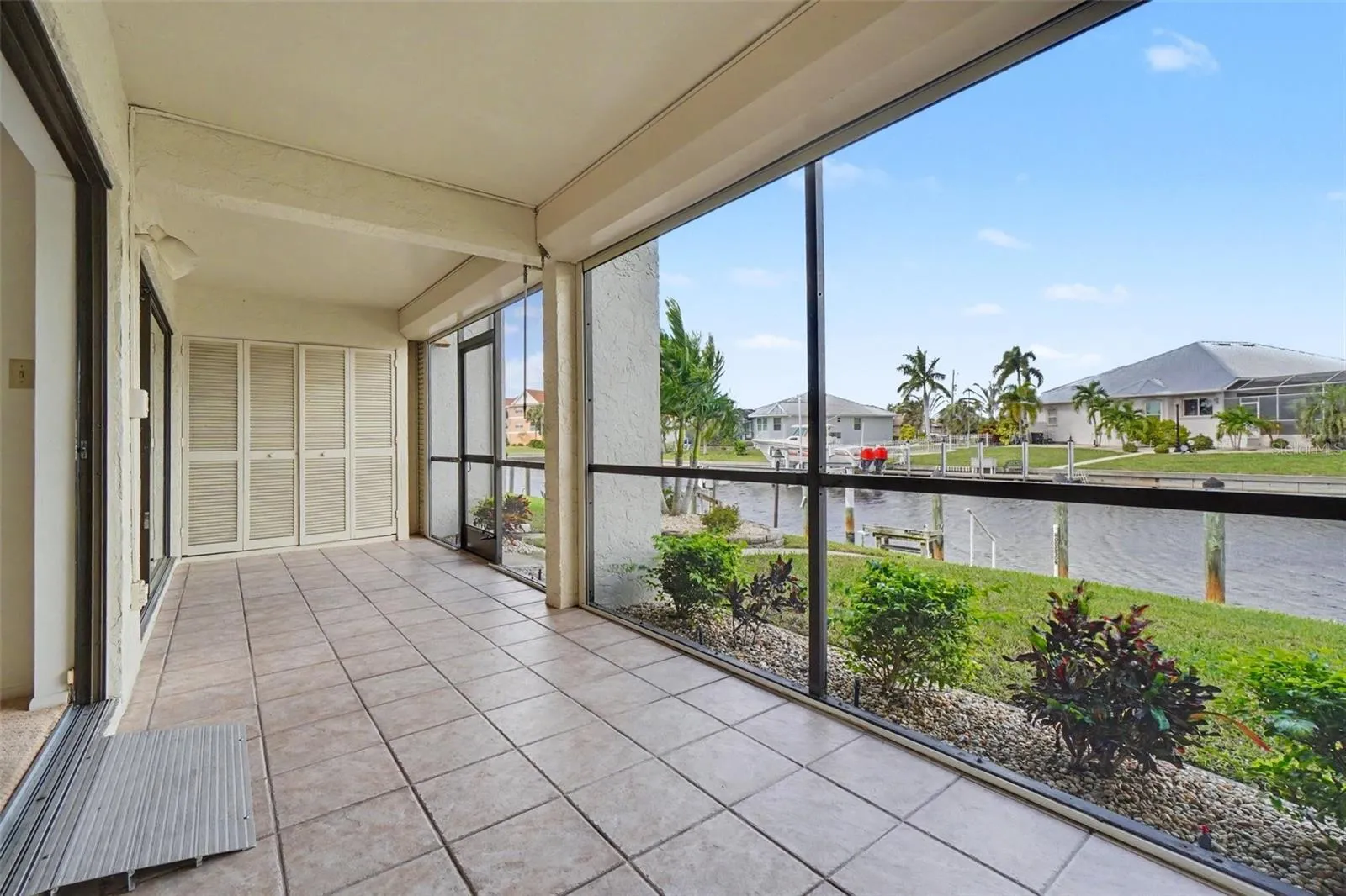 Large screened lanai with tile flooring and electric roll-down shutters, facing the canal and private dock.