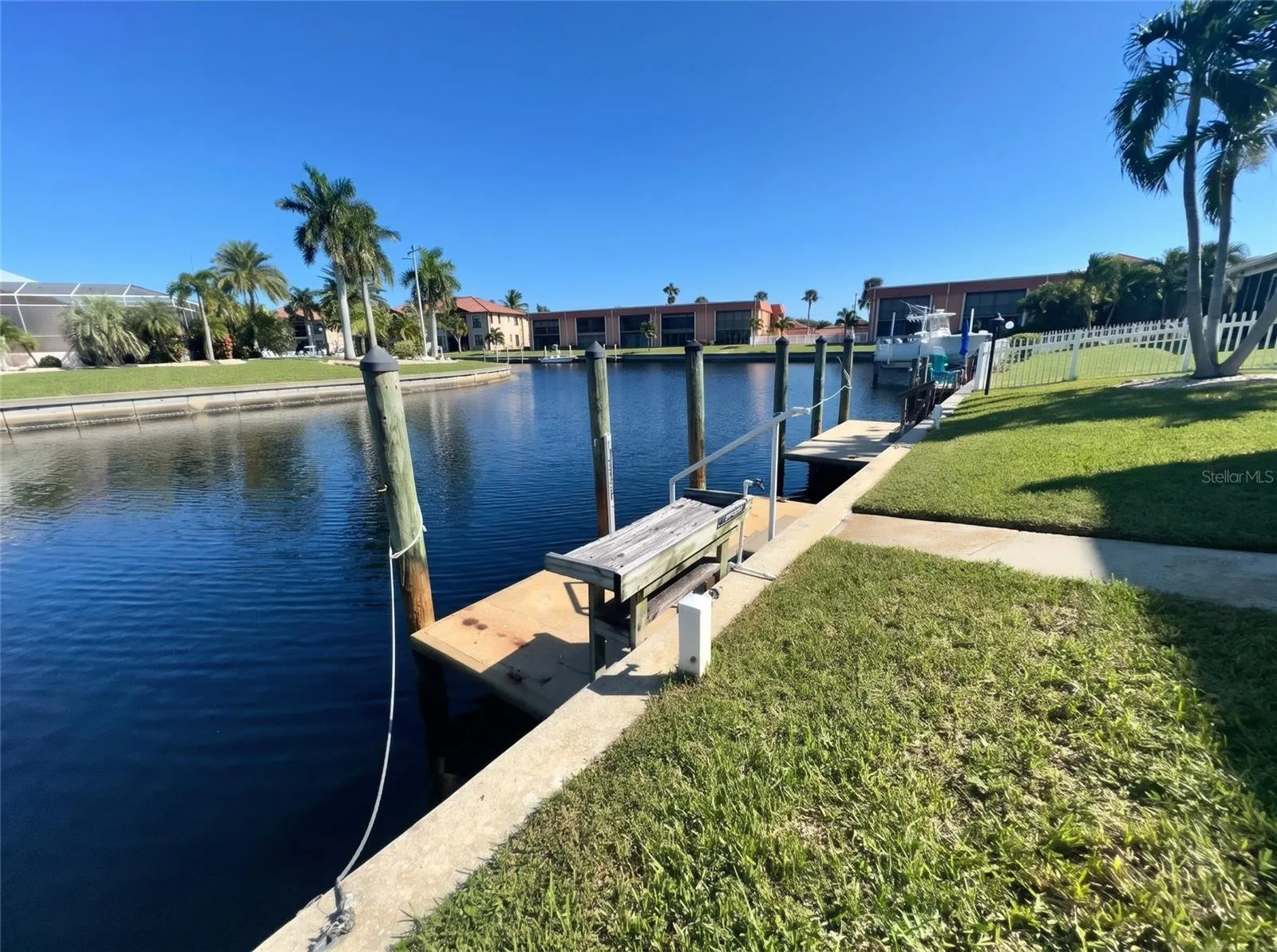 Deeded boat dock at 1423 Mediterranean Dr on a Punta Gorda canal, with dock box, pilings, and steps from the lawn to the water.