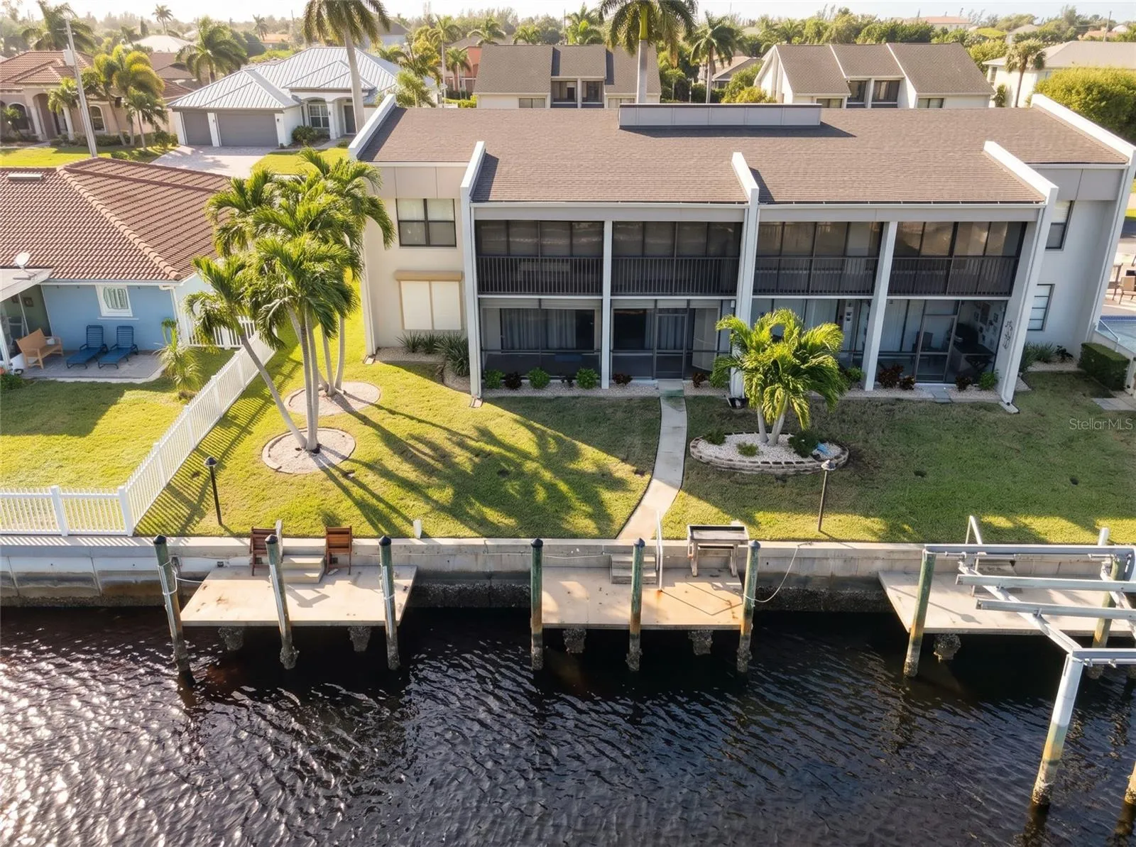 Aerial view of 1423 Mediterranean Dr #B, a first-floor waterfront condo in Punta Gorda, FL, with a lawn leading straight to a private boat dock on the canal.