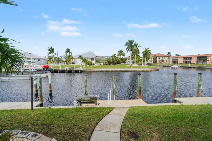 Canal view from the backyard of this Punta Gorda waterfront condo, with the private dock, seawall, and neighboring boat lifts across the water.