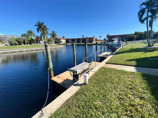 Deeded boat dock at 1423 Mediterranean Dr on a Punta Gorda canal, with dock box, pilings, and steps from the lawn to the water.