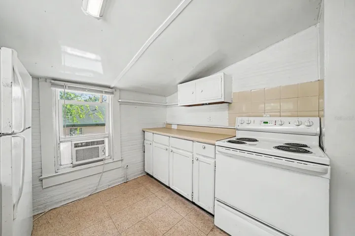 Bright Kitchen with White Cabinetry, Tile Counters & Windows with Natural Light