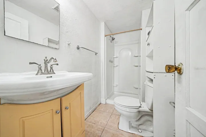 Guest Bath with Yellow Vanity, Shower Enclosure & Ceramic Tile