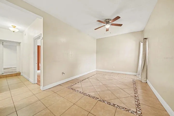 Spacious Living Room with Ceiling Fan, Tile Flooring & Multiple Entry Points