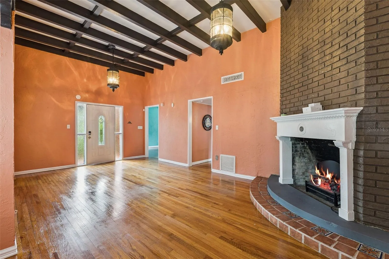 Wood floors, dramatic ceiling beams, and a distinctive corner fireplace