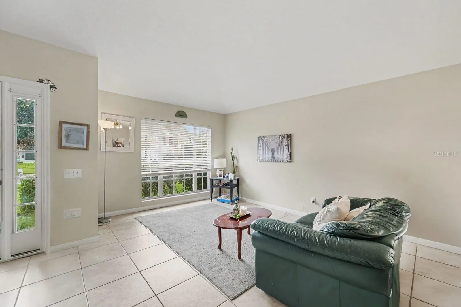 Sunlit Sunroom with Sliding Glass Doors, Tile Flooring &amp; Green Leather Seating