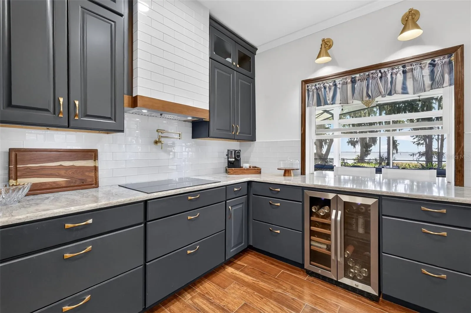 Glass tile backsplash, custom range hood, bar fridge, pot filler and pass through window to the lanai