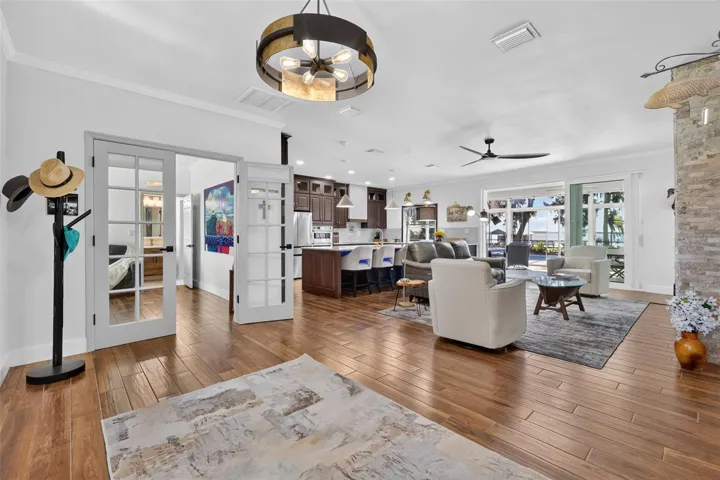 From foyer into living room/kitchen with lake views beyond; bedroom 3 shown through double French doors