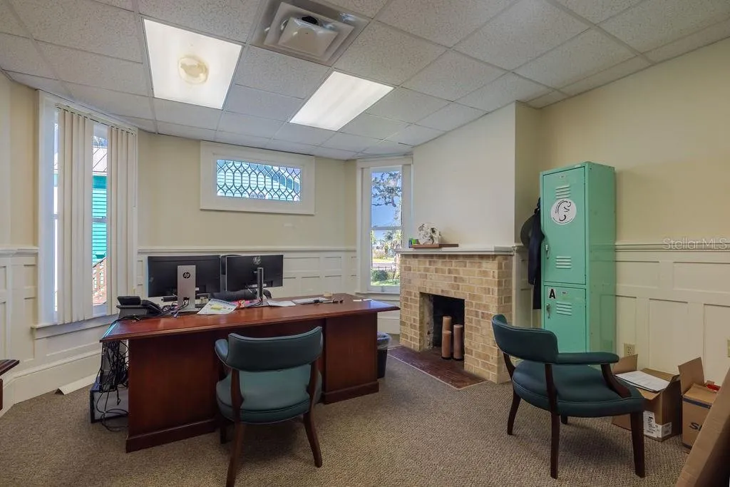 First floor office with stained glass accent window and historic masonry fireplace.