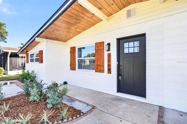 Take a look at the tongue and groove soffits and the wooden shutters for that pop of color.