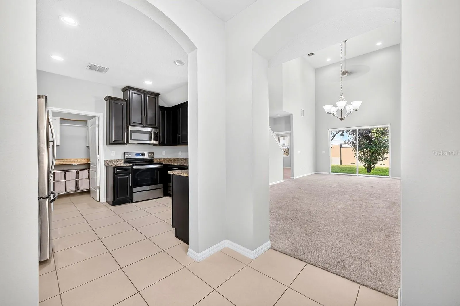 Elegant ARCHED DOORWAYS lead to the Kitchen and the OPEN LIVING and DINING AREA, creating a lovely sense of flow between the main gathering spaces.
