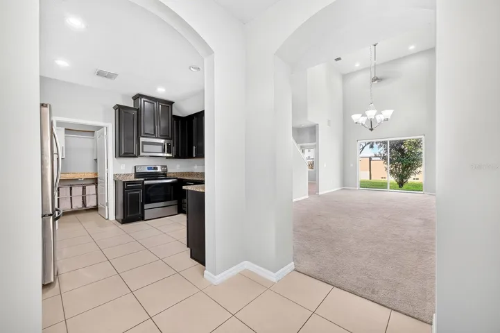 Elegant ARCHED DOORWAYS lead to the Kitchen and the OPEN LIVING and DINING AREA, creating a lovely sense of flow between the main gathering spaces.