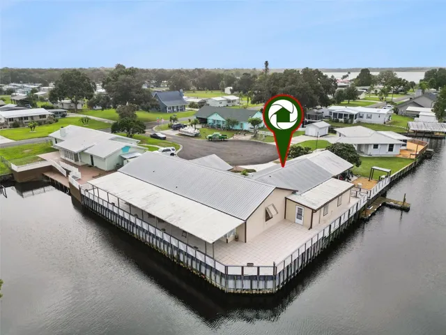 Aerial Rear Deck Pin: High-angle drone perspective featuring a property location pin identifying the home's premier position on the canal point