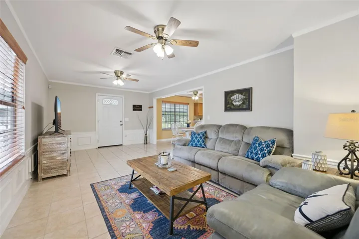 Living Room Perspective: Light-filled family room showing a seamless transition to adjacent living spaces, complete with neutral walls, ceiling fans, and large picture windows.