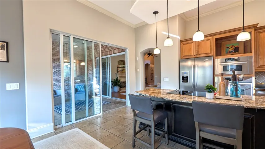Kitchen features an island with seating, and stainless steel appliances.