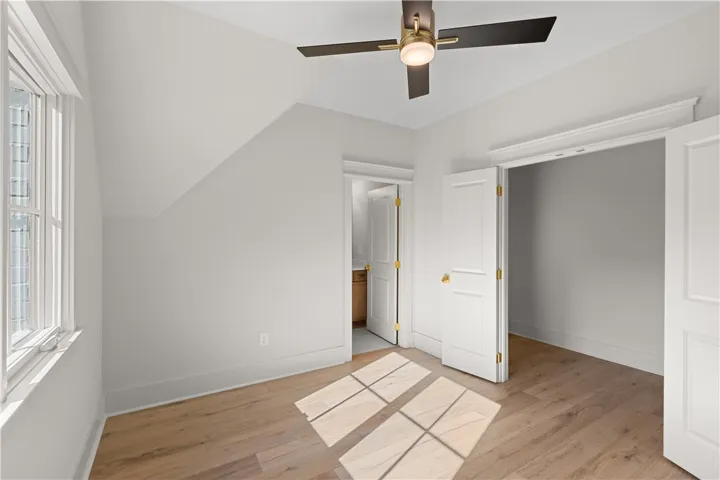 This spacious bedroom offers abundant natural light and warm wood flooring.